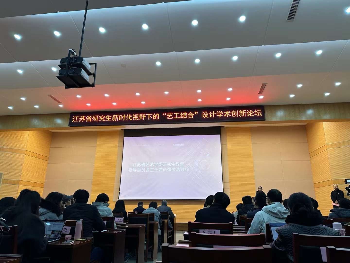 An audience attending a presentation beneath the forum banner.