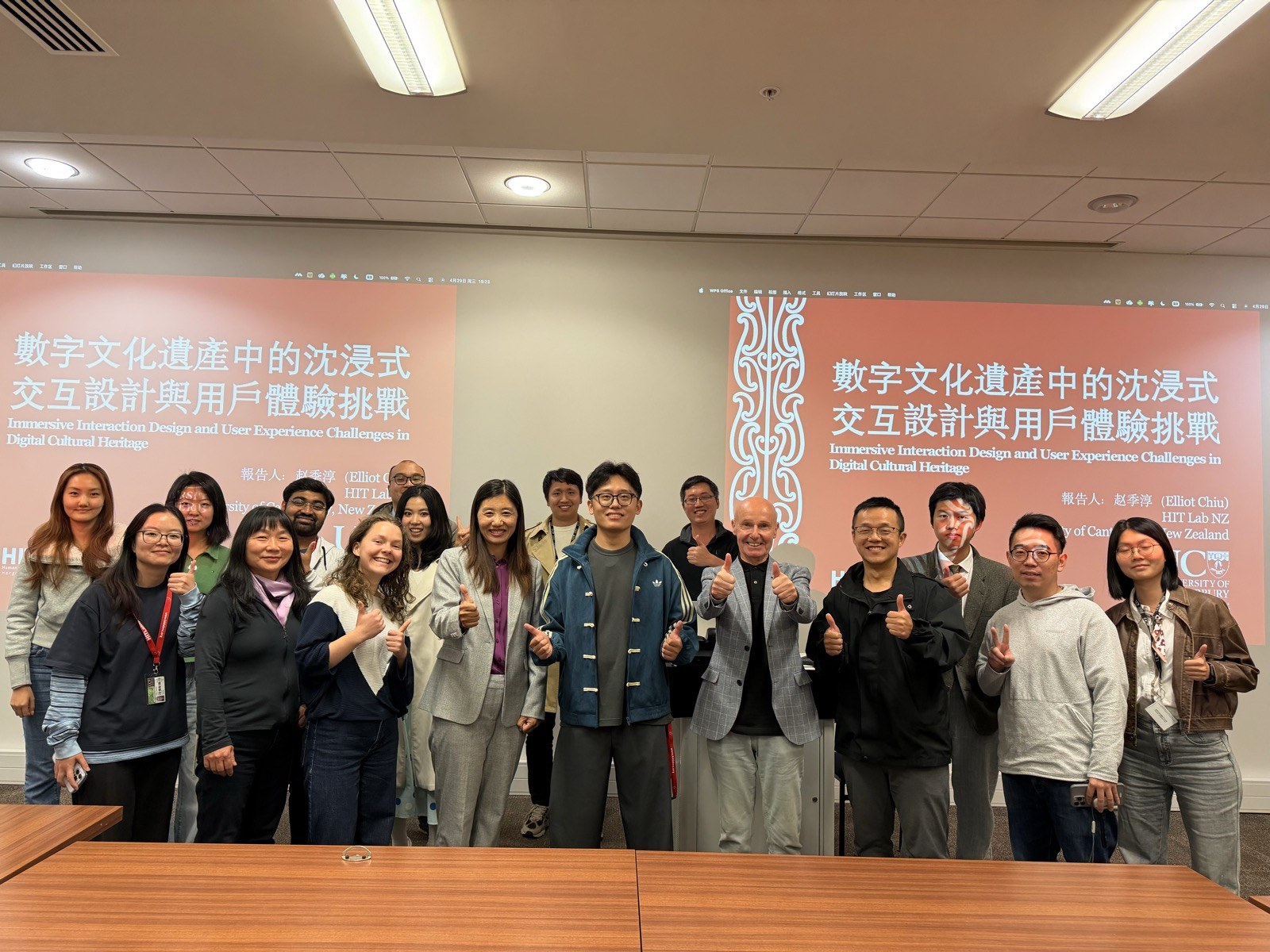 Speaker and attendees posing in front of the lecture title at the University of Canterbury.