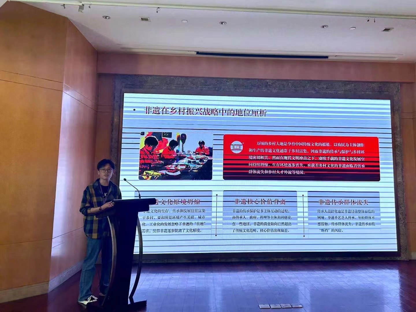A speaker presenting research beside a projected slide.